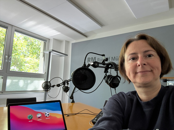 podcast-monika-verspohl Monika Verspohl, vor einem Studio-Mikrofon sitzend.